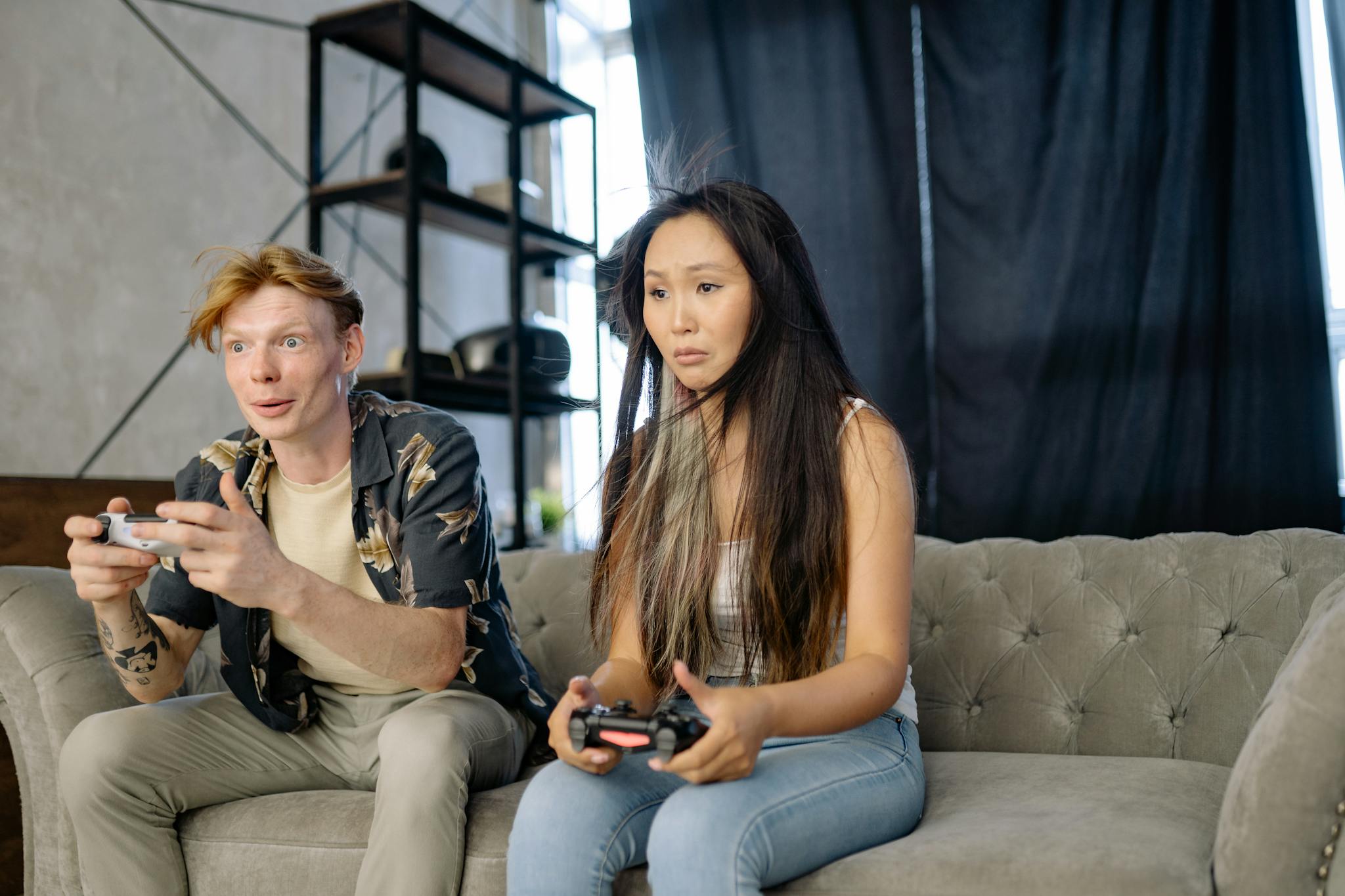 A man and woman playing video games on a couch, immersed in entertainment.