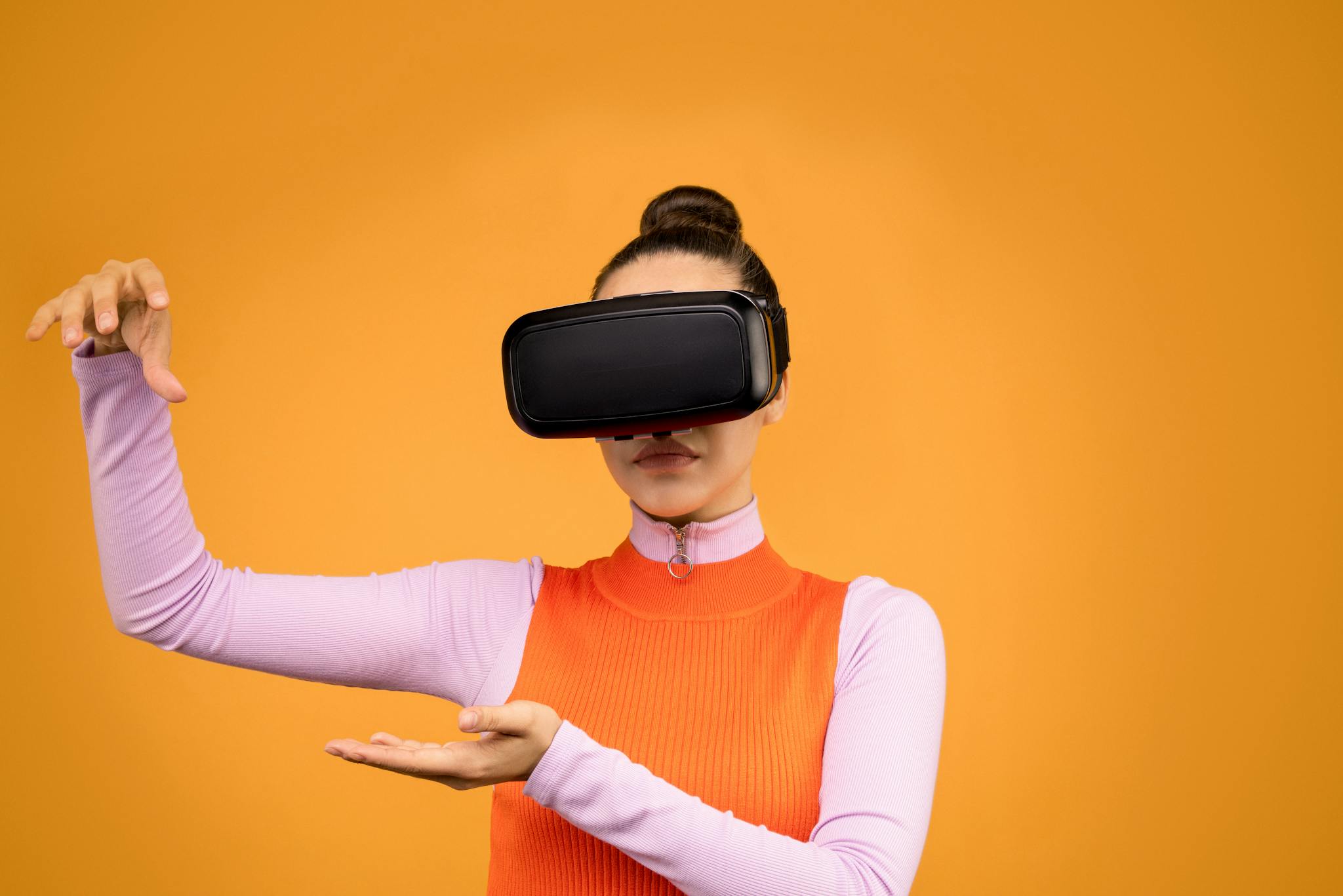 A woman in a vibrant outfit immerses herself in a virtual reality experience against a solid background.