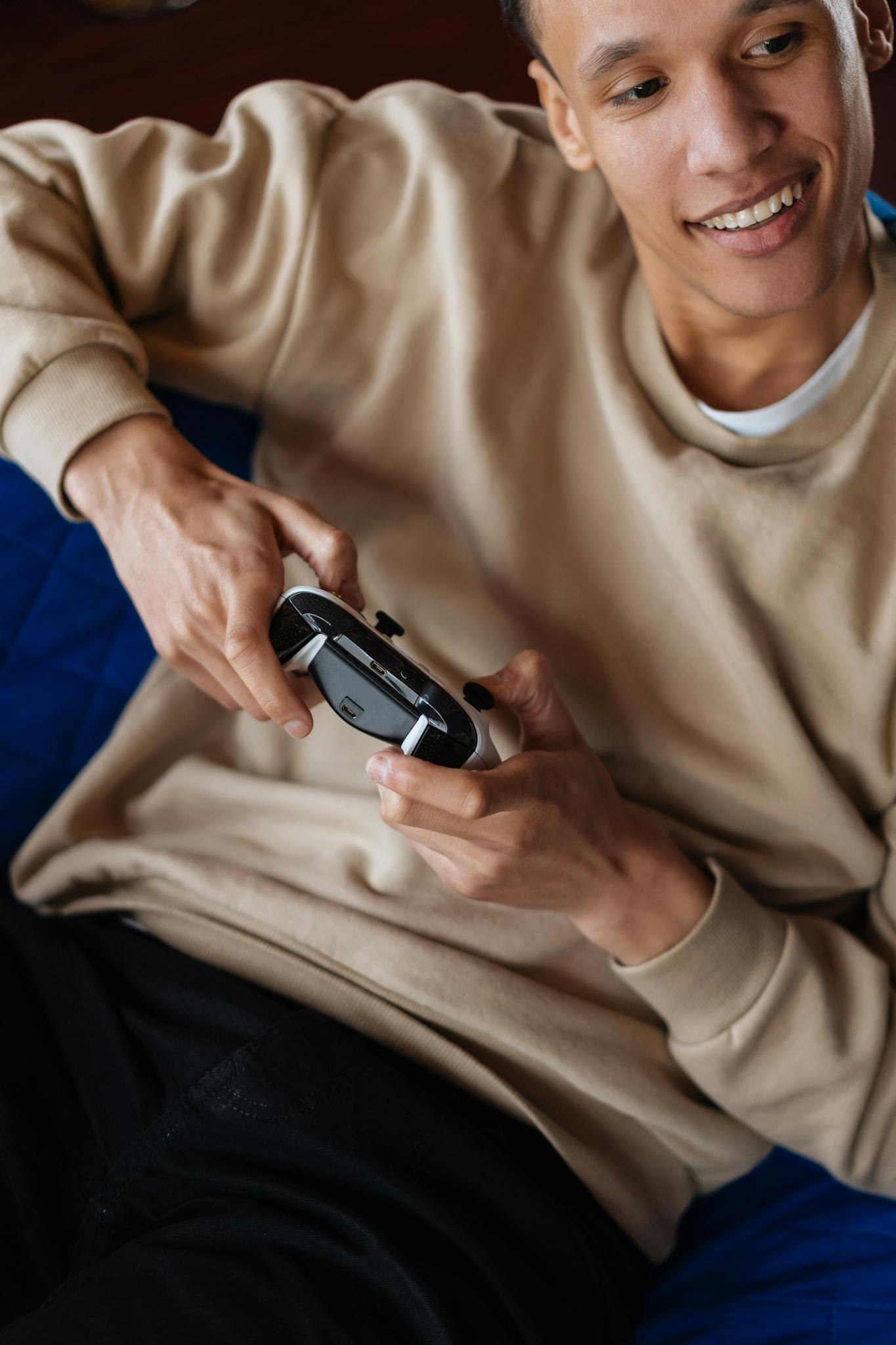 A young man in a sweater enthusiastically playing video games with a controller.