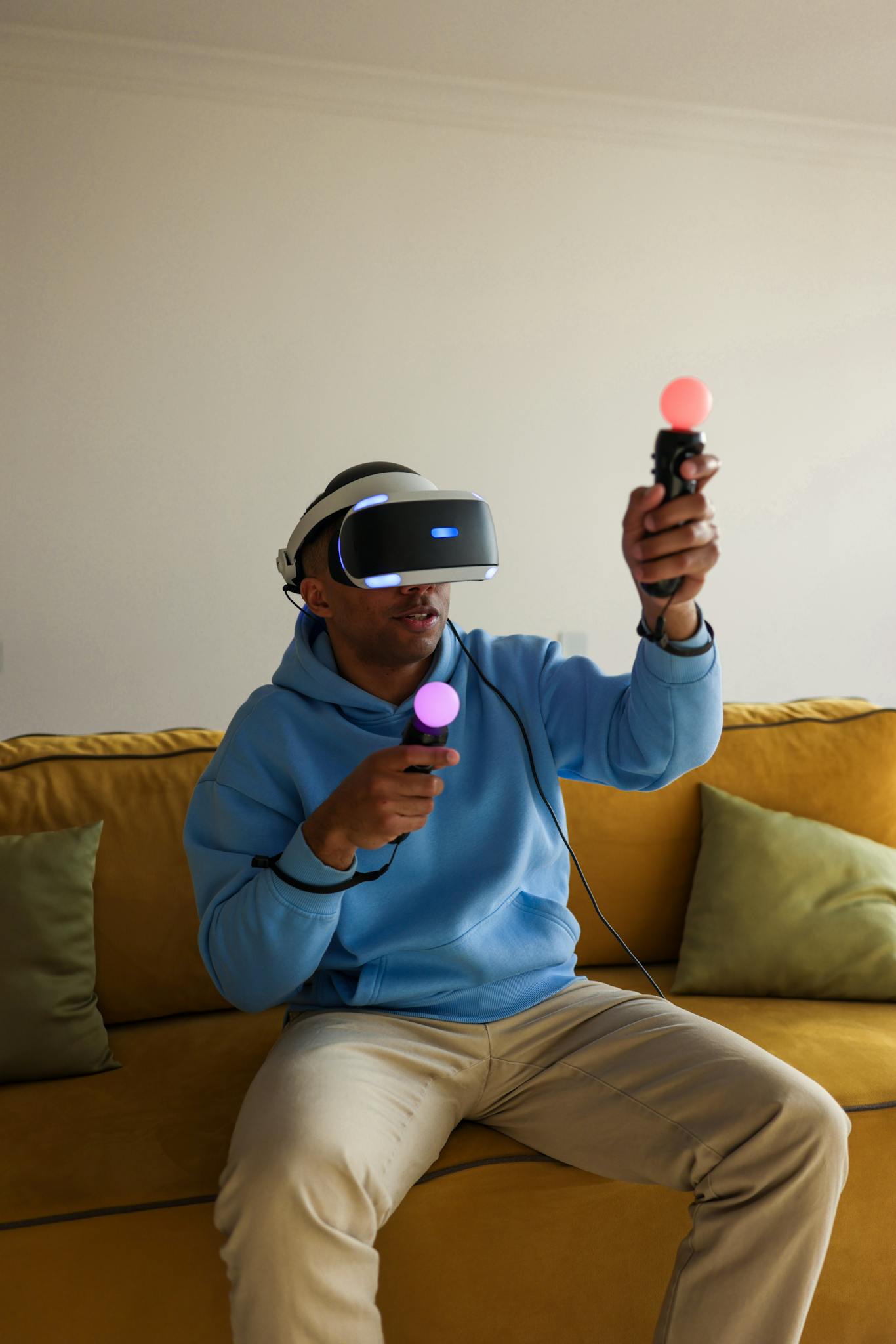 Man with VR headset enjoying gaming on a sofa with motion controllers.