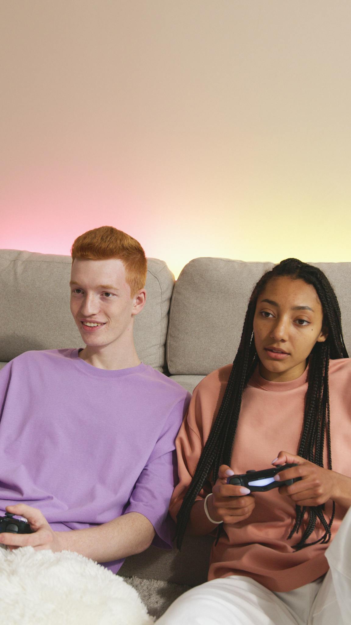 Teenagers relaxing and playing video games on a cozy sofa setup indoors.