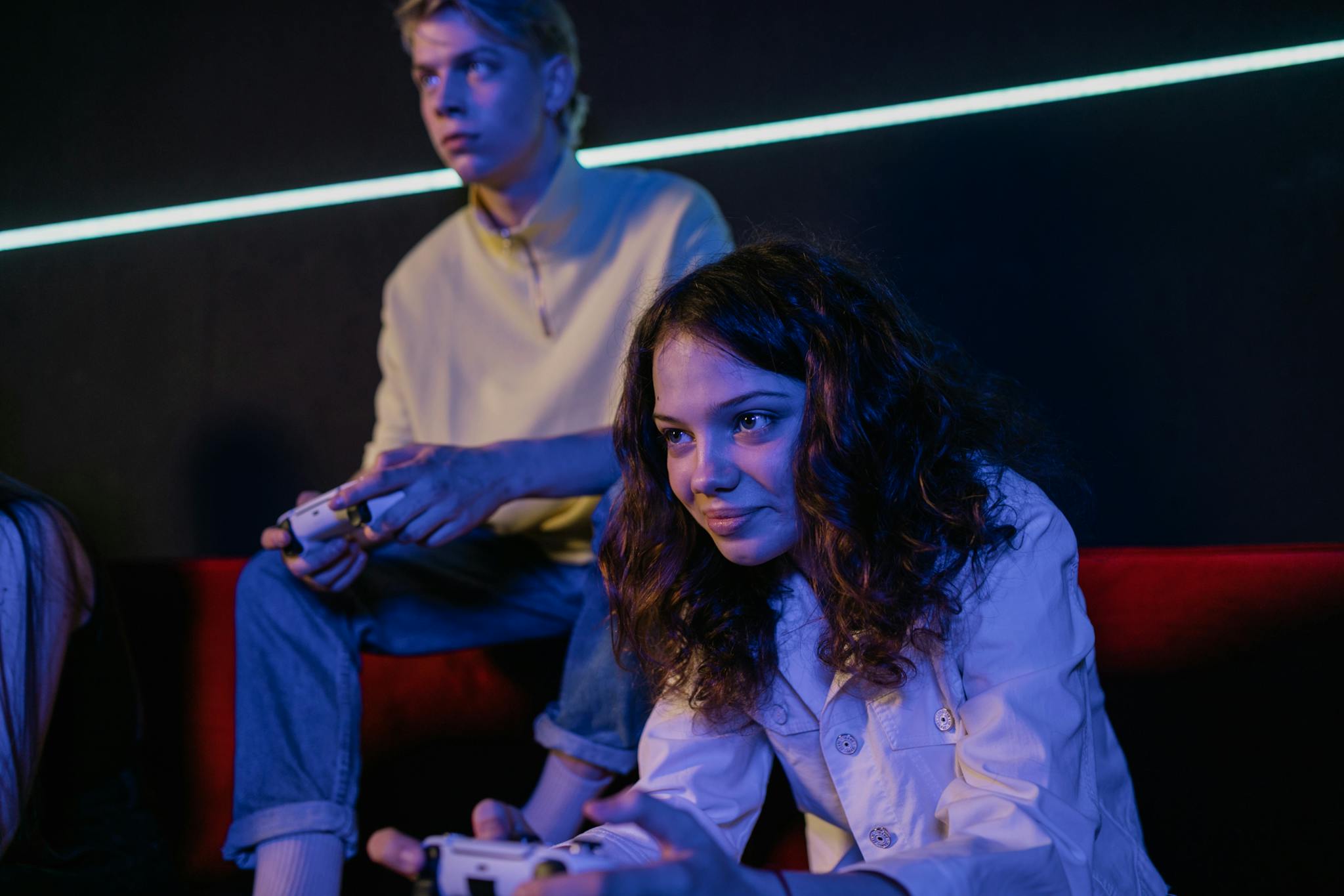 Young adults intensely focused on a video game session with wireless controllers.